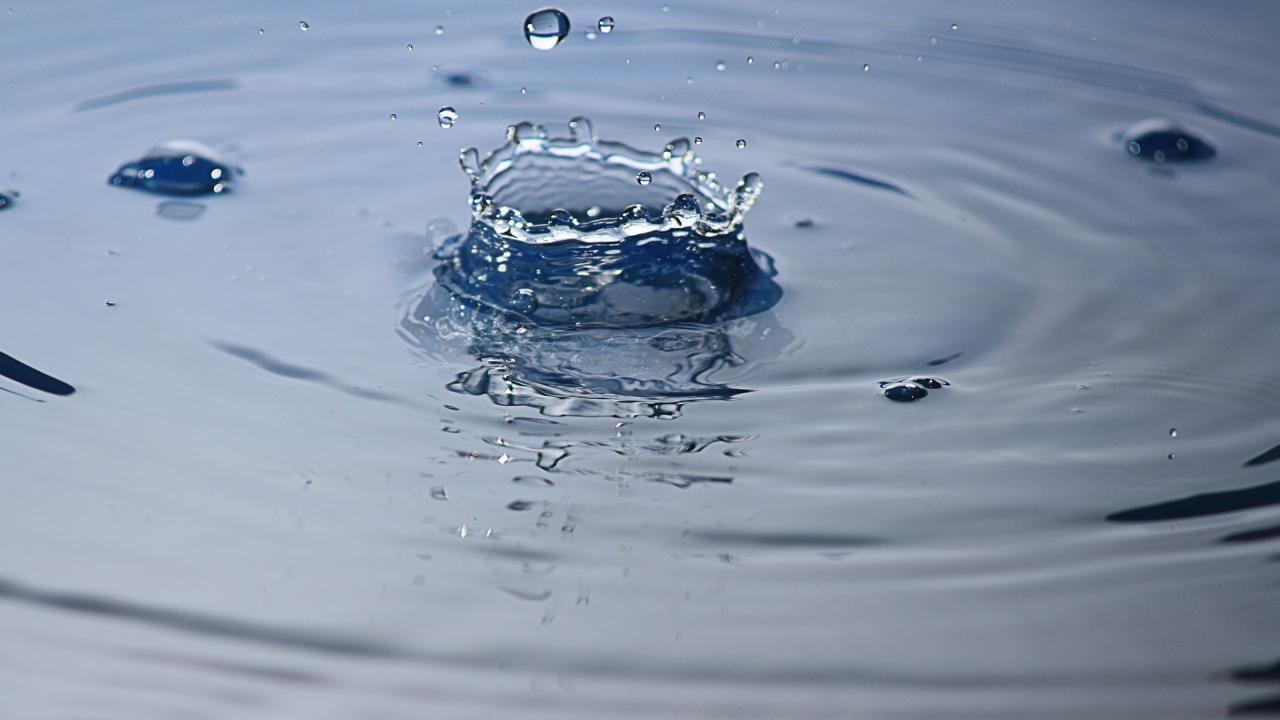One droplet of water falling into a larger body of water
