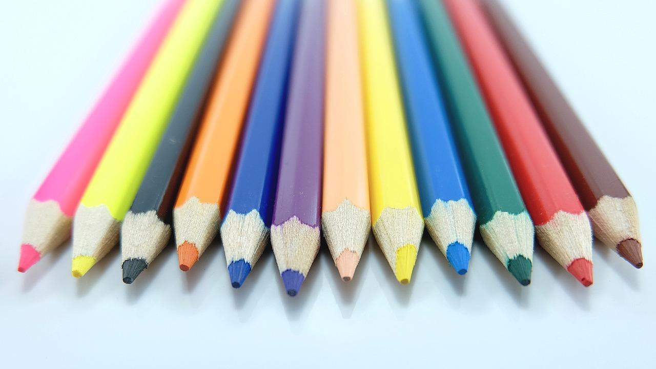 An array of colored pencils lined up side-by-side on a table.