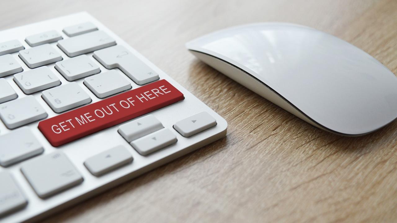 Keyboard and mouse on a desk, the enter key on the keyboard reads 'get me out of here'.