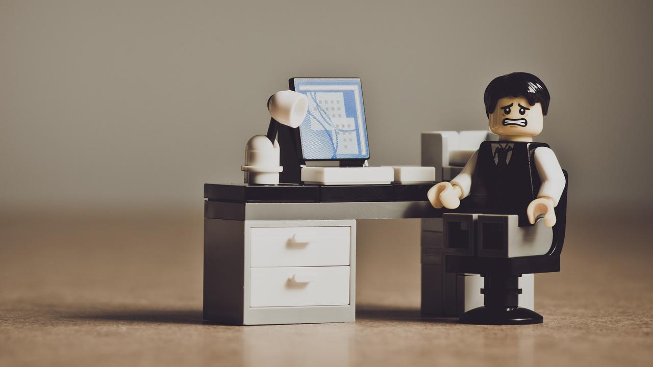 Lego figure sitting at a desk with a look of despair on his face.