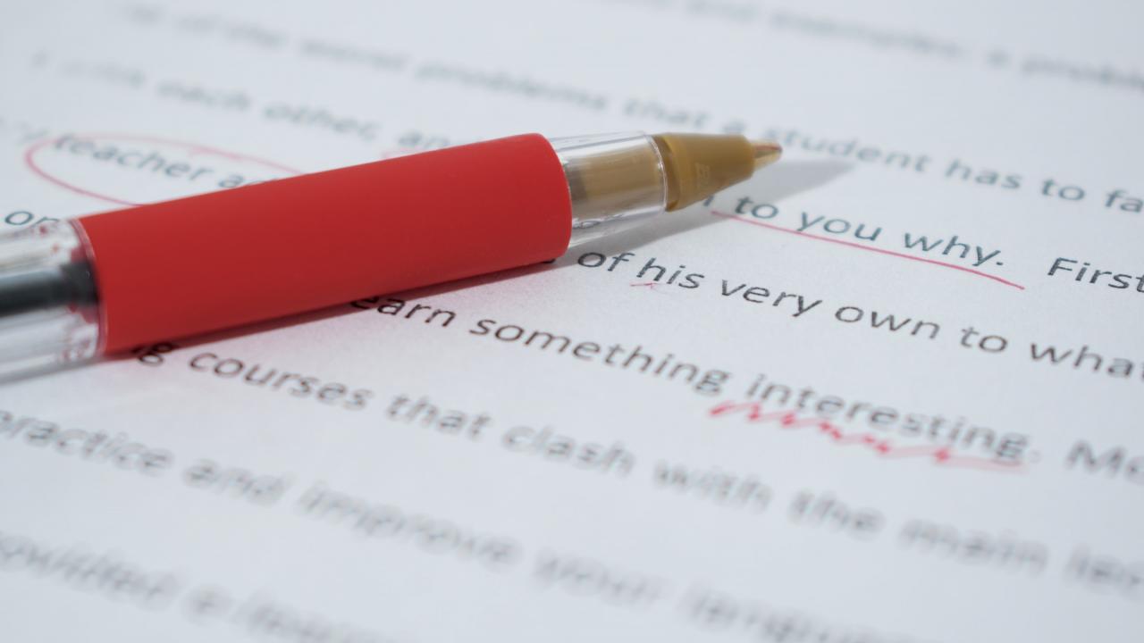 A red pen resting on a marked up page showing corrections to typed text.