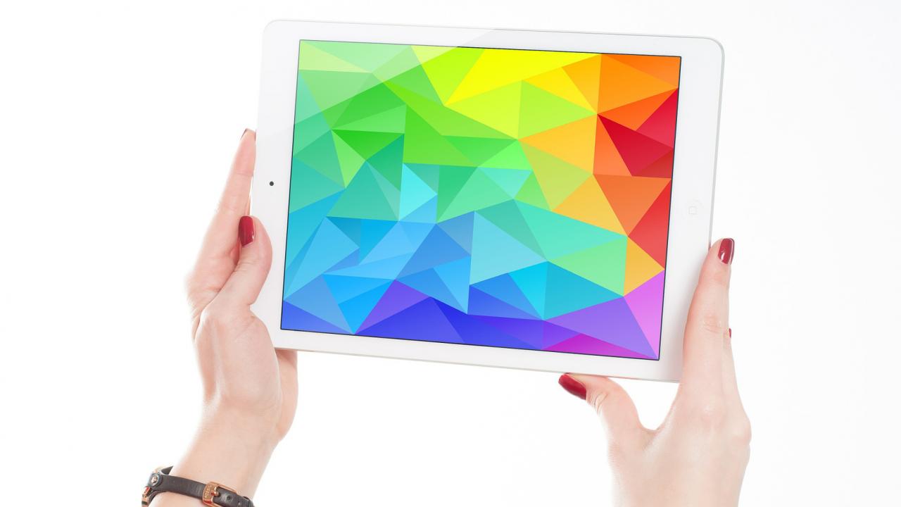 A woman's hands holding up an ipad with a screen displaying a full spectrum of color.