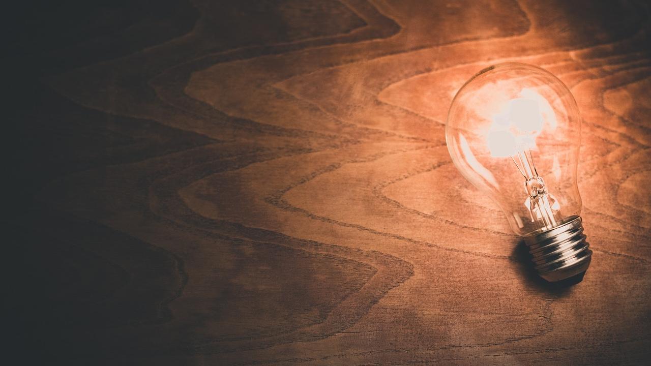 A bright light bulb on top of a wooden background
