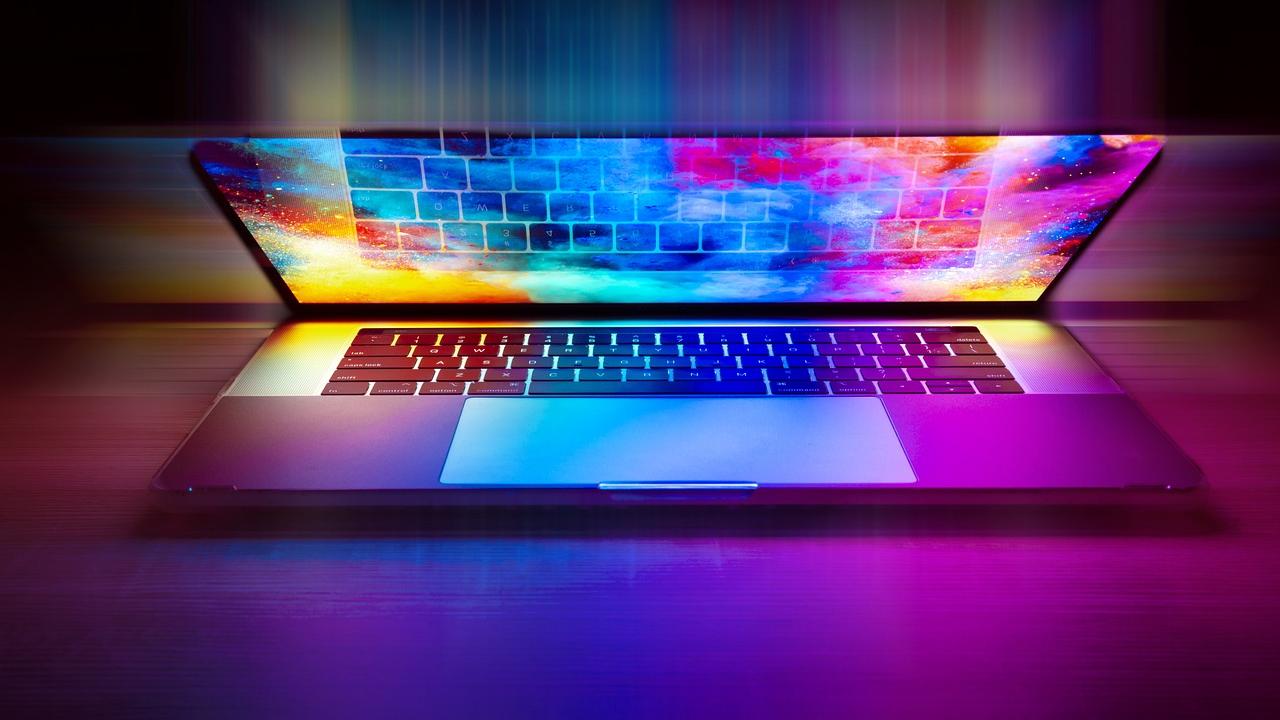 A slightly closed laptop lid exuding a brilliant color display of an abstract pattern and the screen lightly reflecting the keyboard keys. Image by Deactivated on Pixabay.