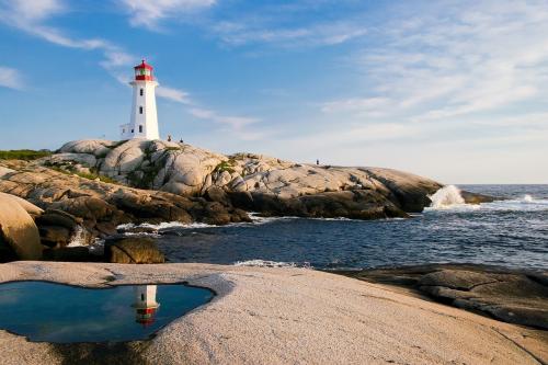 Lighthouse in mid-afternoon sunlight, the view from a sandy coastline. From Pixabay by lumix2004