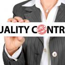 A woman in a business suit holding a sign reading "Quality Control"