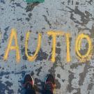 Photo by Goh Rhy Yan on Unsplash. The word 'Caution' is written on the ground.