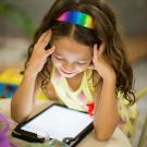 A young girl watches the screen on a tablet. Image by Patricia Prudente at Unsplash