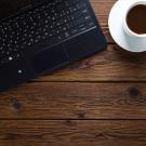 Laptop and a cup of coffee on a wooden tabletop