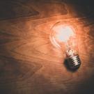 A bright light bulb on top of a wooden background