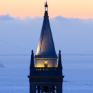 Sather Tower at dusk with the San Francisco Bay and the Golden Gate Bridge in the background.