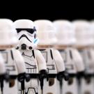 A row of Lego Stormtroopers, all of them facing away from the viewer except for a single one facing forward."