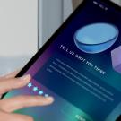 A tablet shows options for a likert five star rating system with a person's fingers selecting their preference